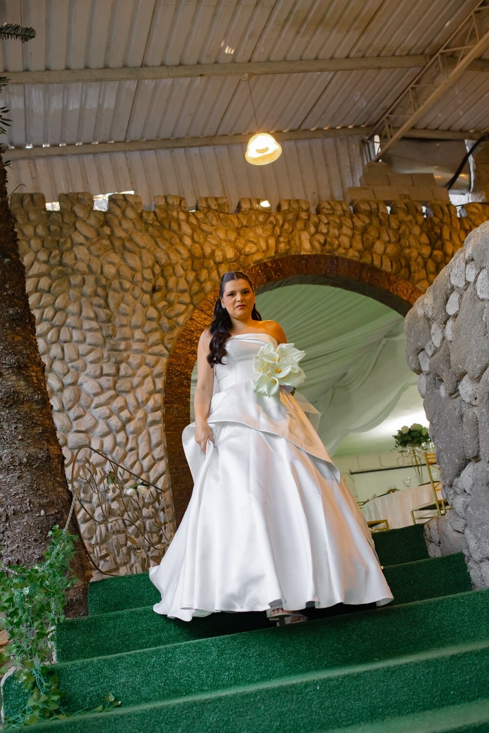 Noiva descendo escadaria de pedra sob arco em estilo castelo colonial