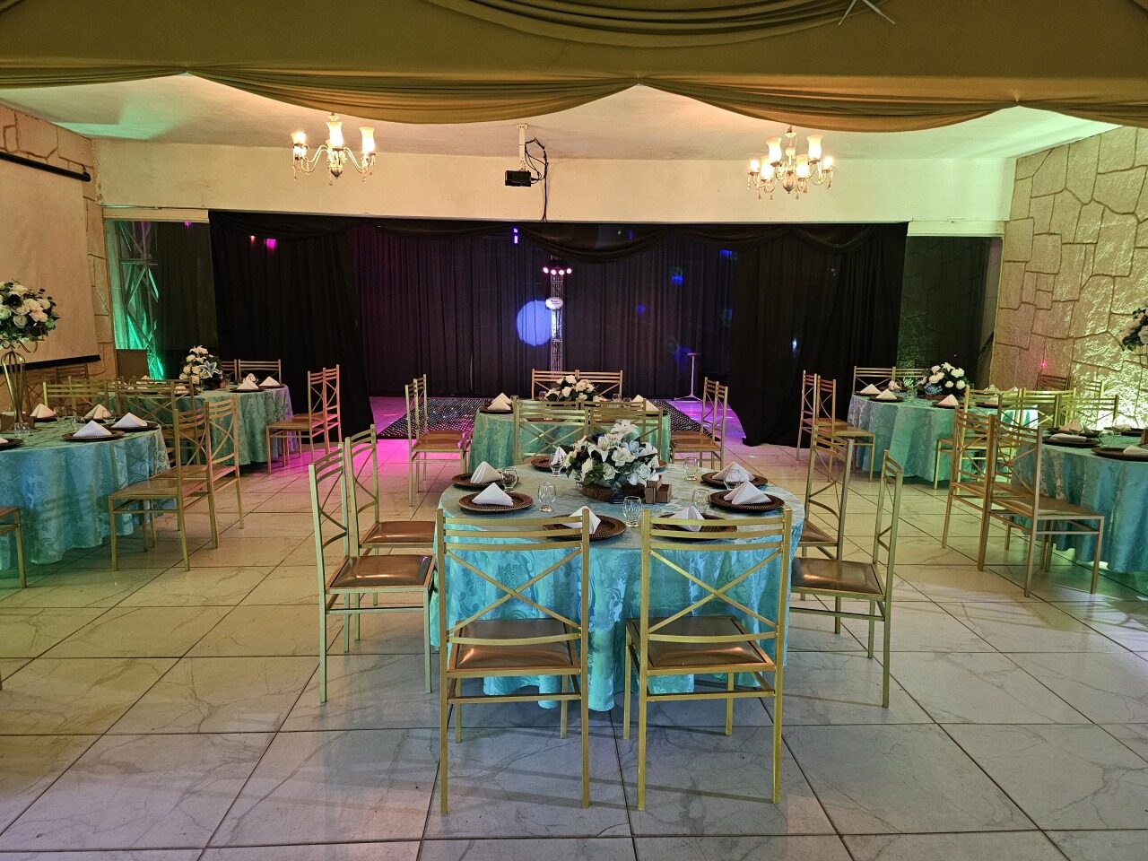 Salão decorado para recepção em tons de verde água e dourado